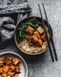 Chopsticks and a bowl with ramen noodles, spinach and tofu; a bowl of tofu is at the side.