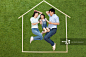 幸福的一家三口躺在草地上的模型房子里_创意图片
