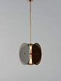 Contrasting an elegant drop with a contained mass in space, this pendant light suspends a trio of tinted glass or brass circles from a brass rod, providing...