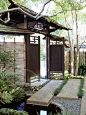 Make an Elegant Entry  A side gate to the garden opens onto a serene, shaded corner screened by a bamboo fence and paved with large slabs of concrete inlaid with rounded black stones. Tufts of deep green mondo grass soften the hardscaping.: