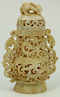 Archaic style Chinese carved jade vase having reticulated body and cover depicting mythical beasts. Has reticulated beast handles to sides. Measures 5" height x 3 1/2" width (12.7cm x 8.9cm).