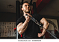 One man young adult caucasian male bodybuilder training arms bicep on the cable machine in the gym holding weight wearing black shirt dark photo real people copy space side view low angle