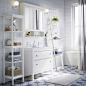白色浴室内装配着 HEMNES 汉尼斯 洗脸池柜、搁板、白色镜柜、条纹浴帘和蓝白双色毛巾。