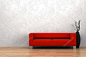 红色的沙发和白墙前的干木花瓶