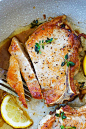 Close up shot of pork chops with garlic butter sauce in a skillet.