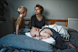 Little girl lying on the bed. A young mother talks to a young son in the background. by Irina Polonina on 500px