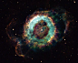 小幽灵星云NGC 6369是很多业余天文学家的最爱。从地球上观察，它是一个黯淡气体云，环绕一颗恒星尸体，座落于蛇夫星座。在这幅“哈勃”2004年拍摄的照片中，小幽灵星云展示了其更多细节，揭示了已死恒星放射出的气体的演化。恒星产生的紫外辐射剥离气体中的原子，让附近区域离子化，形成明亮的蓝绿环。外缘的红色区域离子化程度相对较低。