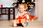 好奇的小女孩在家里打开圣诞礼物图片-商业图片-正版原创图片下载购买-VEER图片库