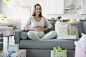 Hero Images 在 500px 上的照片Pregnant woman sitting on sofa surrounded by baby shower gifts