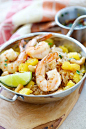 Shrimp topped pineapple fried rice in skillet with lime