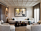 Elegant living room with ornate coffered ceiling, abstract artwork, and plush furnishings.