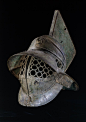 Helmet - bronze. Period/Culture: Roman. Date 1stC. Description Bronze gladiator's helmet. It has a grille of linked circles to protect the face, and a broad brim to protect the back and sides of the head. At the front of the helmet is a medallion of Hercu