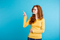 Close up Portrait young beautiful attractive redhair girl happy with something and pointing finger. Blue Pastel Background. Copy space. Free Photo