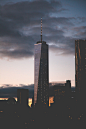 A dim shot of a skyscraper with a long spire in New York on an evening