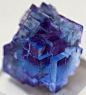 Fluorite (CaF2) Blue Fluorite with Phantom Purple - Macro view of a very small but special fluorite crystal speciment, only 1 1/4" tall, captured through the glass display case. This shows a clear blue outer row of translucent blue cubes grown over a
