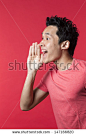 Side view Portrait of a happy Chinese/Asian man shouting. Red background. - stock photo