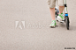 孩子的脚特写镜头在滑行车的。 男孩骑马滑行车在公园在晴朗的夏日。 生活方式概念