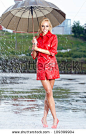 Woman in raincoat smiling as she holds umbrella