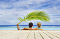 Photograph Caucasian couple shading themselves under palm frond in swimming pool by Gable Denims on 500px