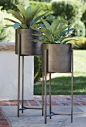 Handcrafted iron planters with warm antiqued bronze finish are framed inside an architectural stand with slender legs and tripod crossbar supports. 100% ironAntique bronze finishAccommodates a 9" pot (no drainage opening)For indoor or outdoor useMade