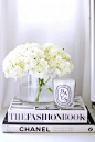 Hydrangeas and candles atop fashion coffee table books.: 