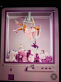 This may contain: a display case filled with stuffed animals and a woman in a pink dress hanging upside down