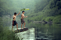Two boys are fishing happily at a river in the countryside.