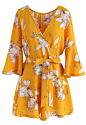 Bold Blooms Floral Wrapped Playsuit in Yellow  : It’s play time AND slay time when you slip into this wrapped playsuit. The bold yellow and huge floral print make this the perfect vacation ensemble. 

- Floral pattern 
- Mid-length flare sleeves 
- Wrappe