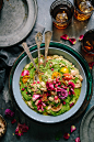 Bowl of green pesto dip topped with tomatoes, herbs, and flowers