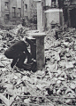 A postman emptying the pillar box the morning after a heavy bombing raid in London 1940