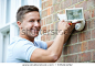 Security Consultant Fitting Security Light To House Wall