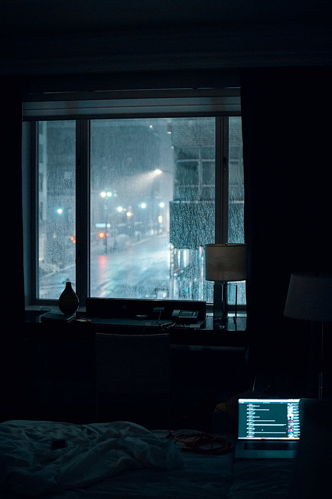 下雨夜，笔记本电脑在房间里的床上打开