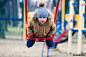 Cute little boy riding on swing in park and looking at camera