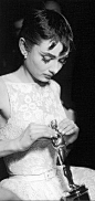 Audrey Hepburn looking down at the Best Actress Oscar on her lap awarded for her role in “Roman Holiday” during Academy Awards, 1953.