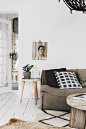 The unframed artwork is just pinned on the wall, and the rustic table and textured grey planter are easy-going accessories. White walls and white floors in this art deco apartment create a cocoon for the stylist-owner’s signature collection of casual sofa