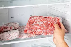 一个人从冰箱里拿出冻肉。