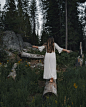 woman in white dress standing on brown tree log during daytime