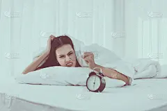无聊的年轻亚洲女人讨厌压力，早上6点起床在床上，闹钟