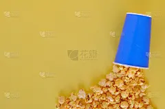 焦糖爆米花在蓝色的纸桶在黄色的背景。