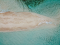 An aerial shot of a sandbar, exotic, white sand and turquoise water.