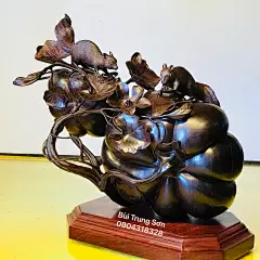 This may contain: a bronze sculpture on a wooden base with leaves and flowers in the shape of an apple