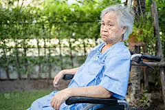 亚洲老年或老年妇女病人在轮椅上公园，健康的医疗观念强。