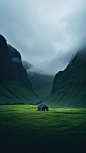 This may contain: a house in the middle of a green field with mountains in the backgroud