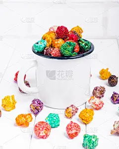 色彩鲜艳的糖果爆米花，白色背景。水平图像的垃圾食品，水果味的爆米花在旧金属杯。五颜六色的，彩虹的，糖