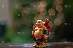 笑快乐佛像站在潮湿的木材与散焦金色和黄色光效果背景。