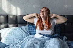 美丽快乐的年轻女子醒来后在床上伸懒腰。22、好梦，早安，新的一天，周末，假日概念