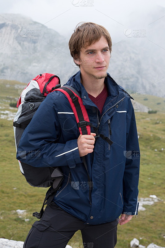 一个年轻人背着背包在山里徒步旅行