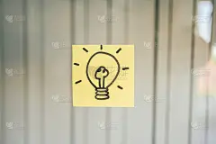 手绘灯泡，画在一个黄色的便利贴在玻璃板与复制空间。