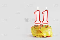 十一年纪念日。生日纸杯蛋糕，白色燃烧的蜡烛，红色边框的数字11。浅灰色背景与复制空间