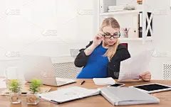 怀孕的商业女性在工作中阅读报纸